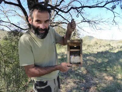Mann (Ramon) mit einem Nistkasten vor einem Baum.